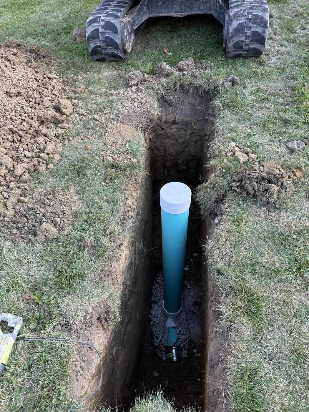 Capped sewer cleanout access riser installed upright inside an excavated trench
